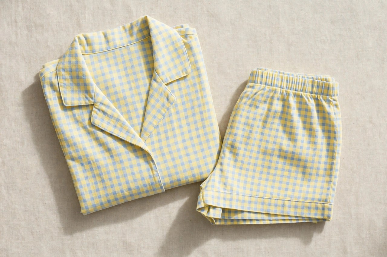 Neatly folded women's cotton PJs in a casual short set style in cheerful soft colors on a clean neutral background