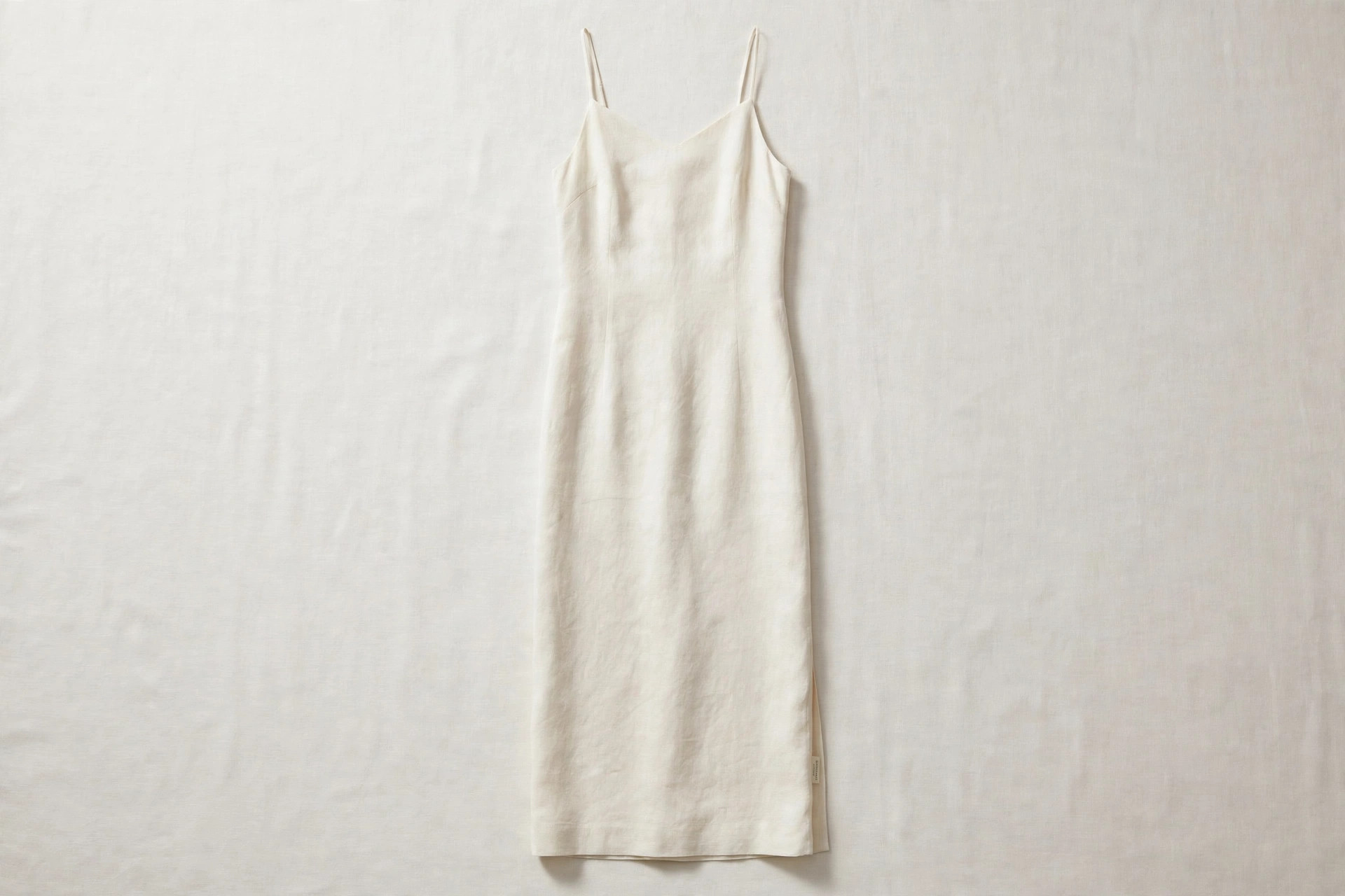 Women's column dress in ivory fabric shown flat in one long straight line from shoulder to hem, product photography with no people