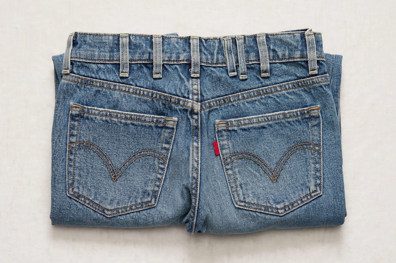 A pair of women's vintage-style Levi jeans folded to show the back waistband, arcuate pocket stitching and red tab detail
