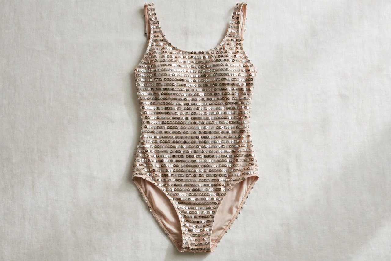 Women's sequined swimwear garment laid flat showing rows of small shiny disks on swim fabric