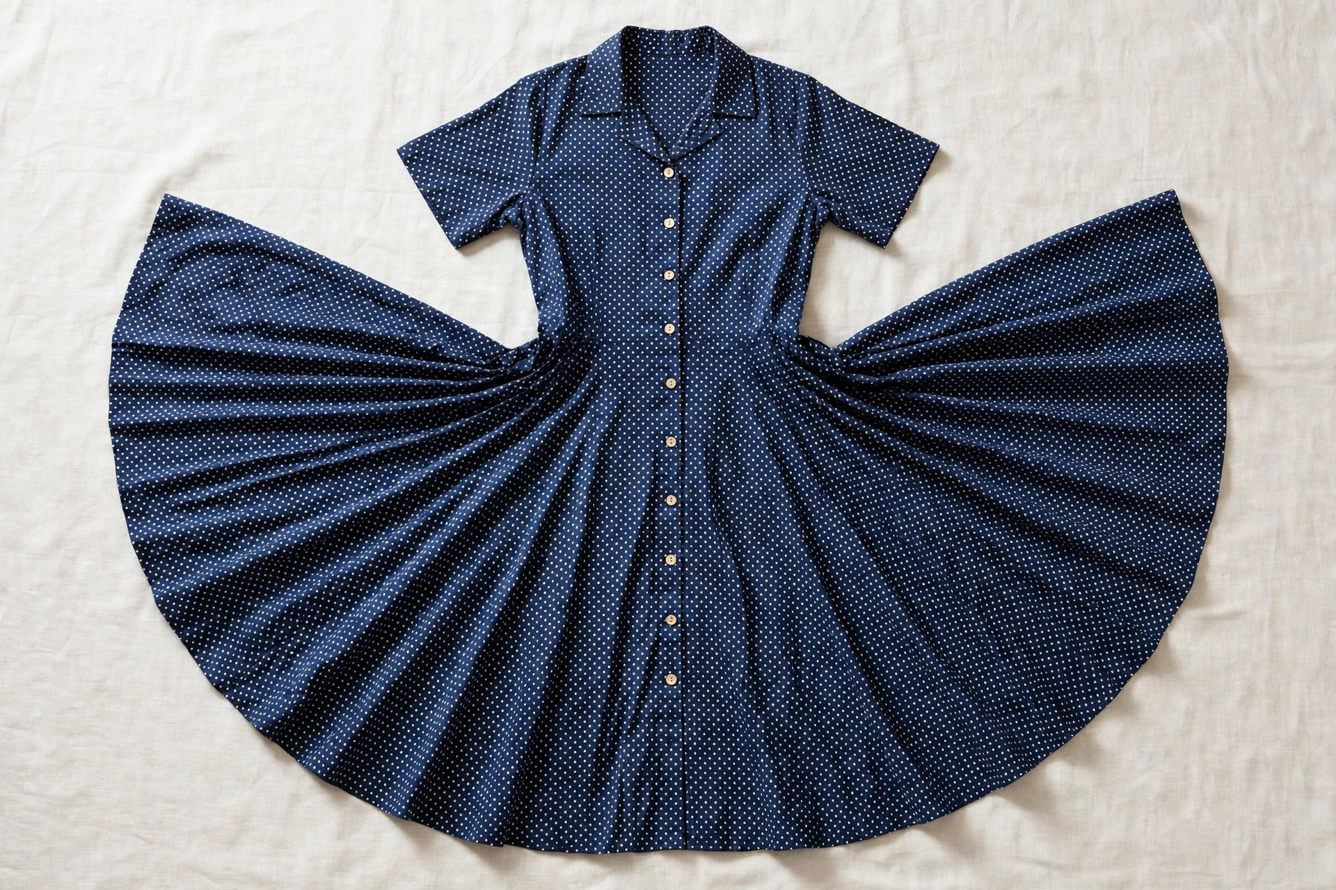 Women's swing dress in polka dot fabric shown flat with the skirt spread wide to show its full circular swing, product photography with no people