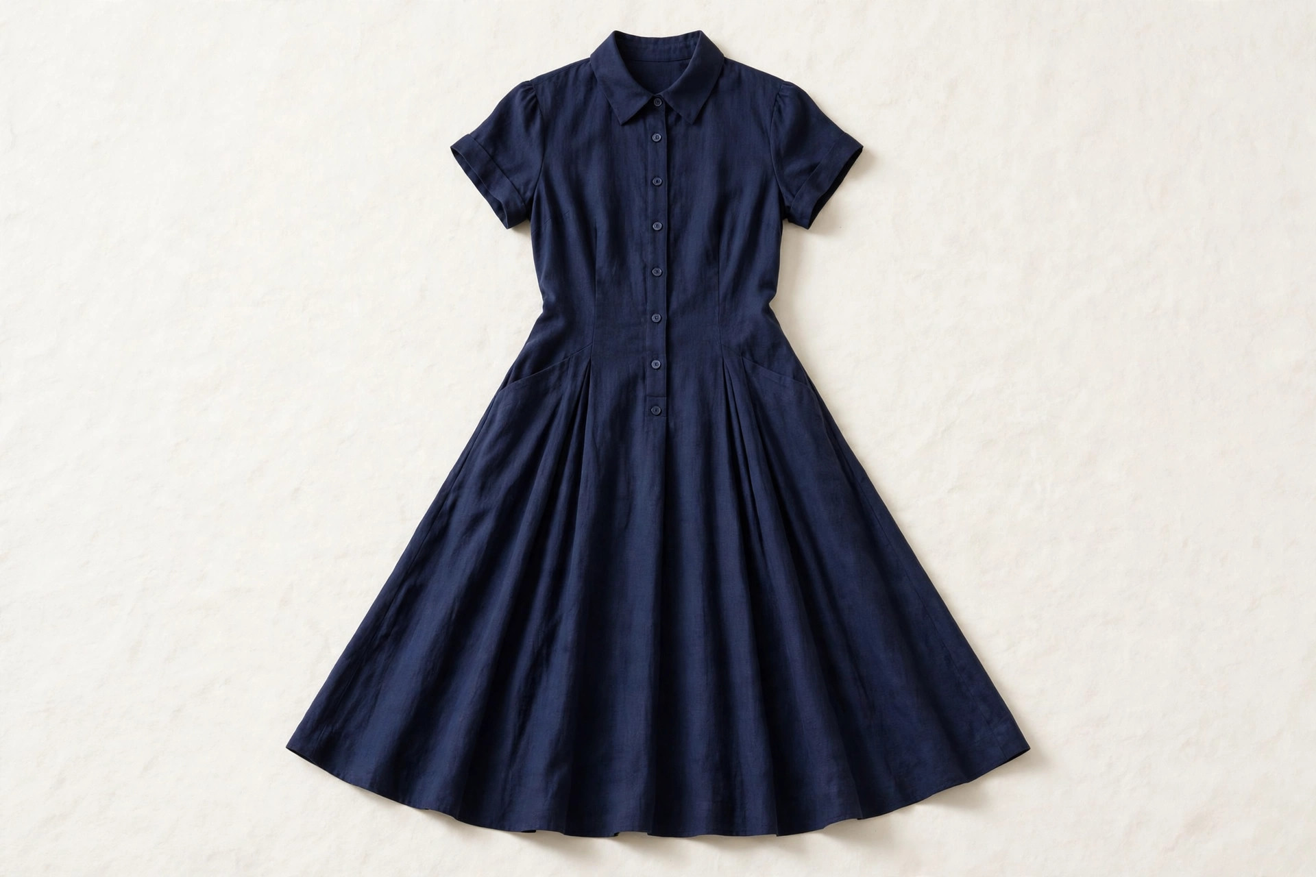 Women's tea length dress in navy fabric laid flat, the full skirt ending mid-calf between knee and ankle, product photography with no people