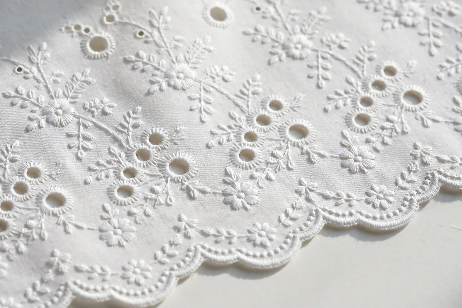Broderie anglaise whitework fabric with cutwork eyelets, floral embroidery and scalloped edge