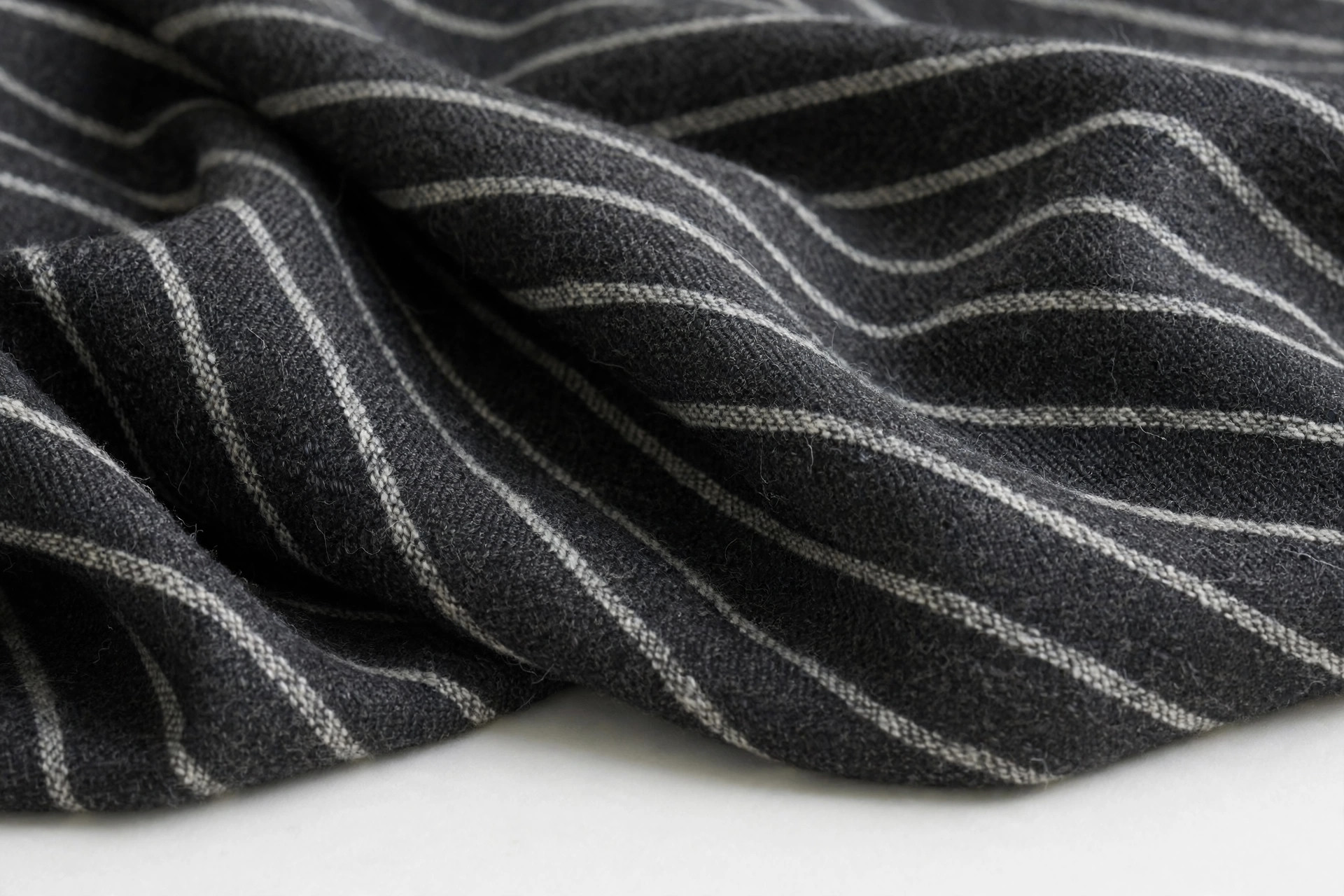 Dark charcoal suiting fabric with soft white chalk stripes woven in