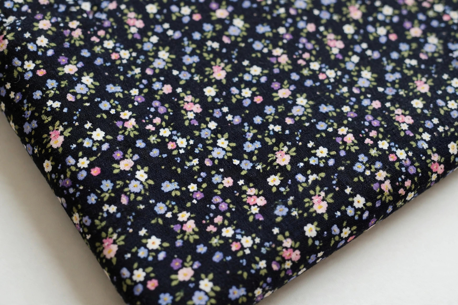 Ditsy floral print fabric with tiny scattered small flowers on a dark ground