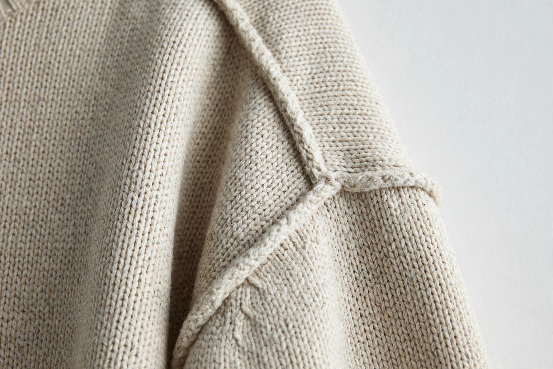 Close-up of a drop shoulder seam sitting low on the upper arm of an oversized sweater