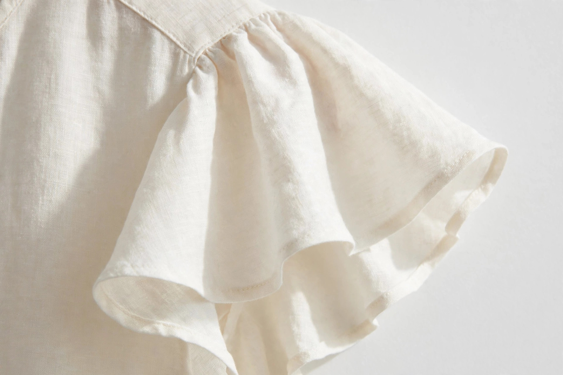 Close-up of a short flutter sleeve flaring softly from the shoulder of a blouse