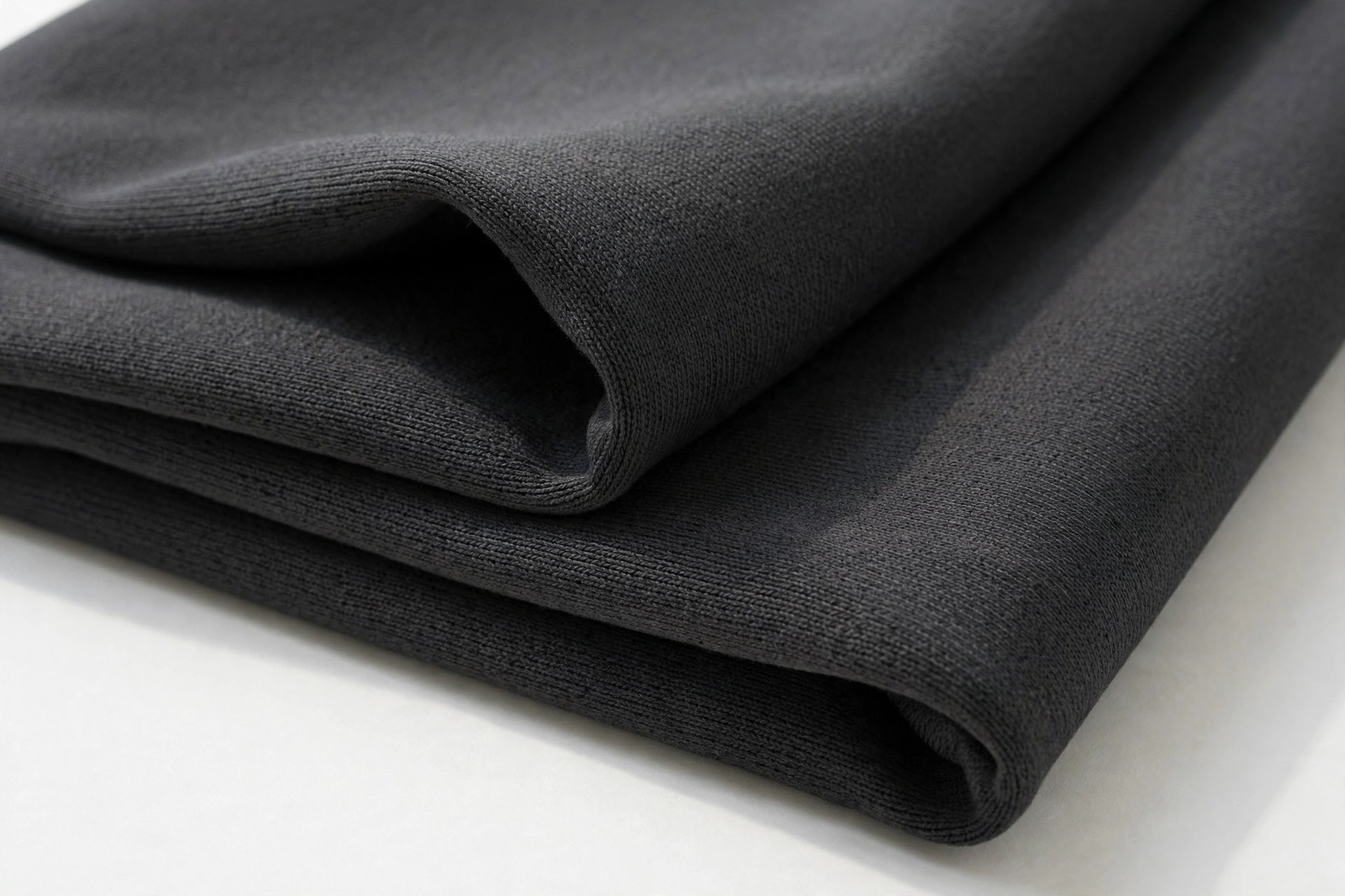 Charcoal ponte double knit fabric swatch showing smooth firm surface, folded to show body