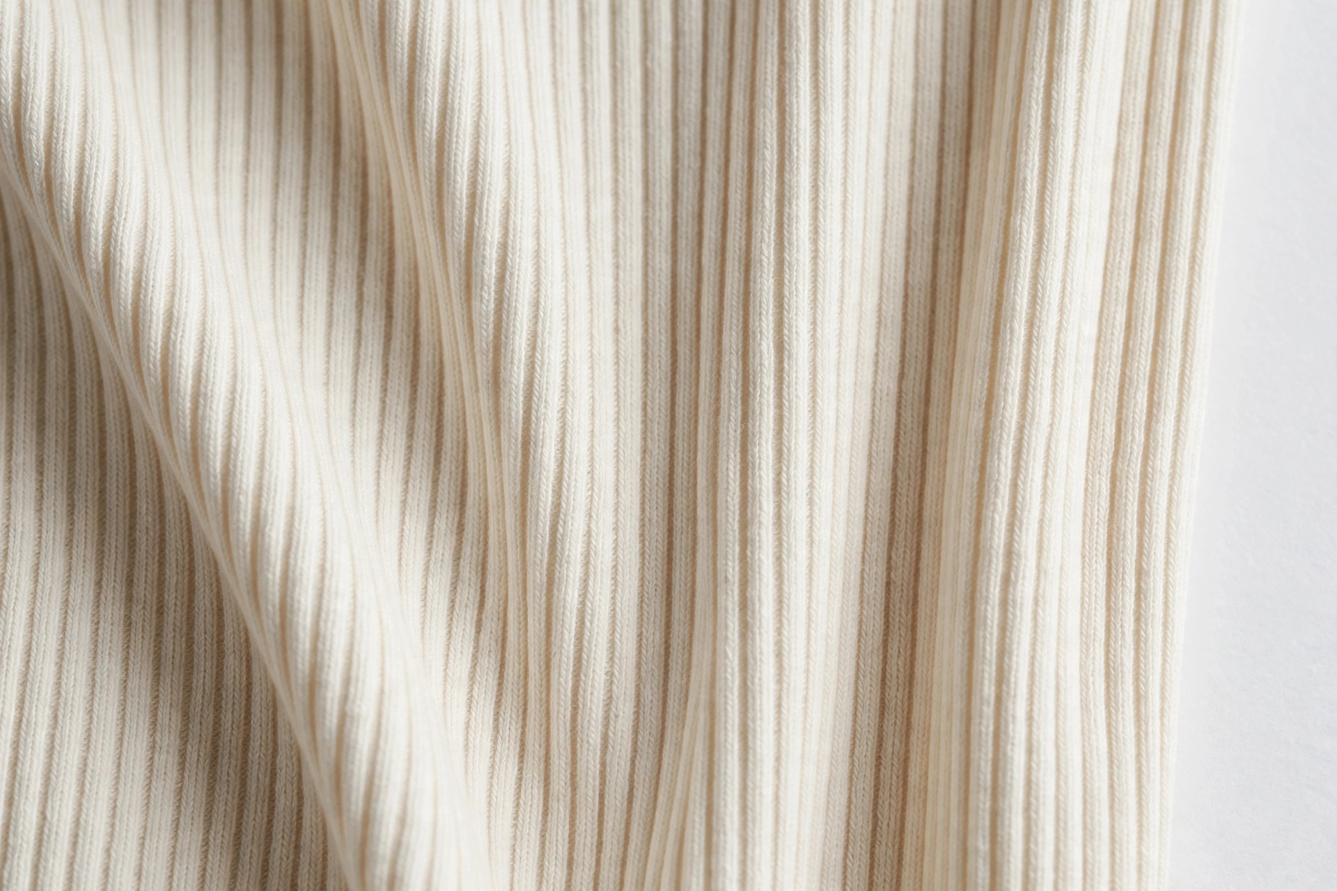 Close-up of cream rib knit fabric showing clear vertical ribs and stretch