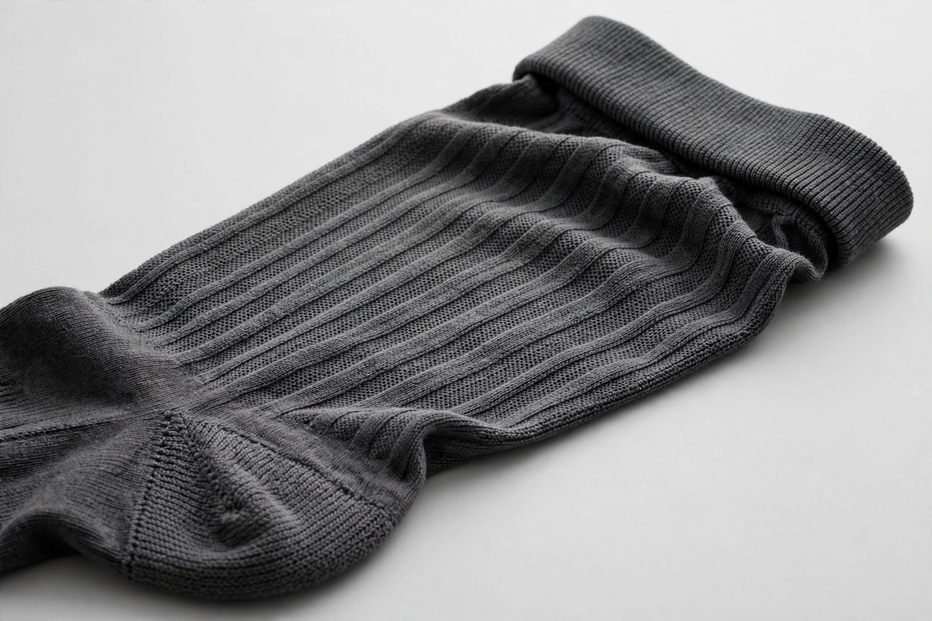 Close-up of a knee-high compression stocking's graduated knit texture and reinforced heel laid flat on a studio background