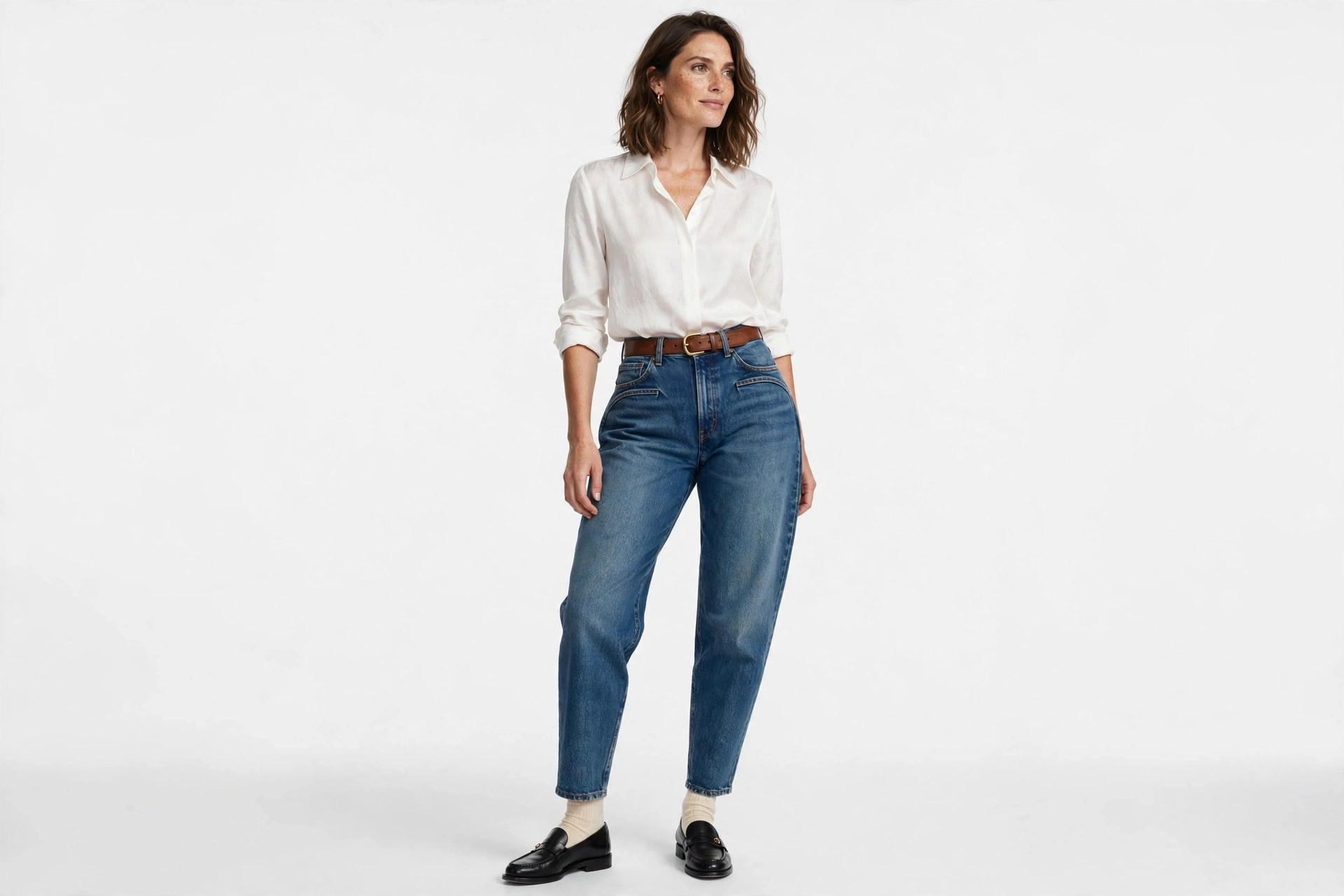 Woman wearing barrel jeans with a tucked-in blouse and loafers