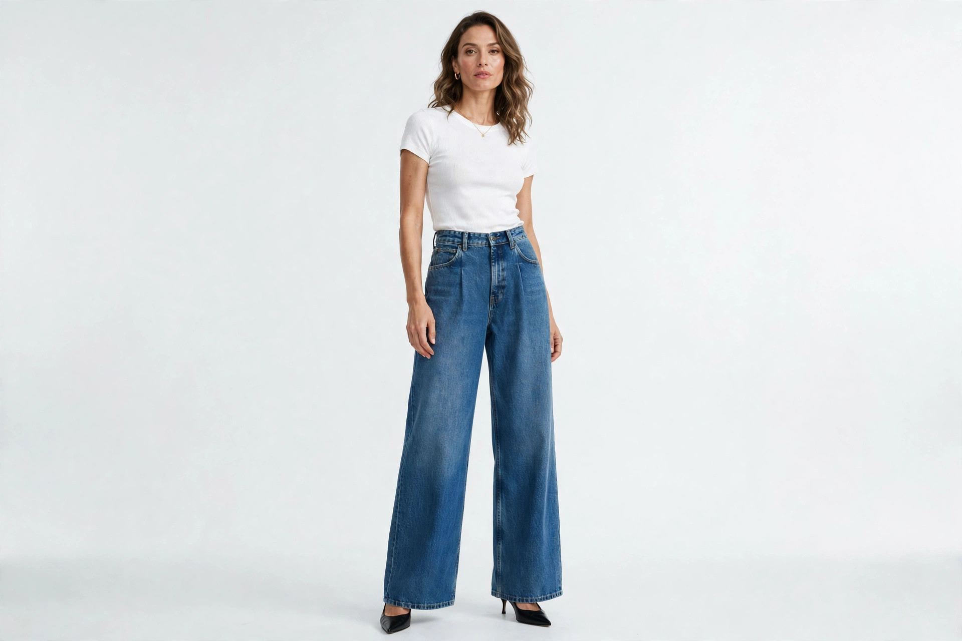 Woman wearing wide-leg jeans styled with a fitted white top and pointed-toe heels