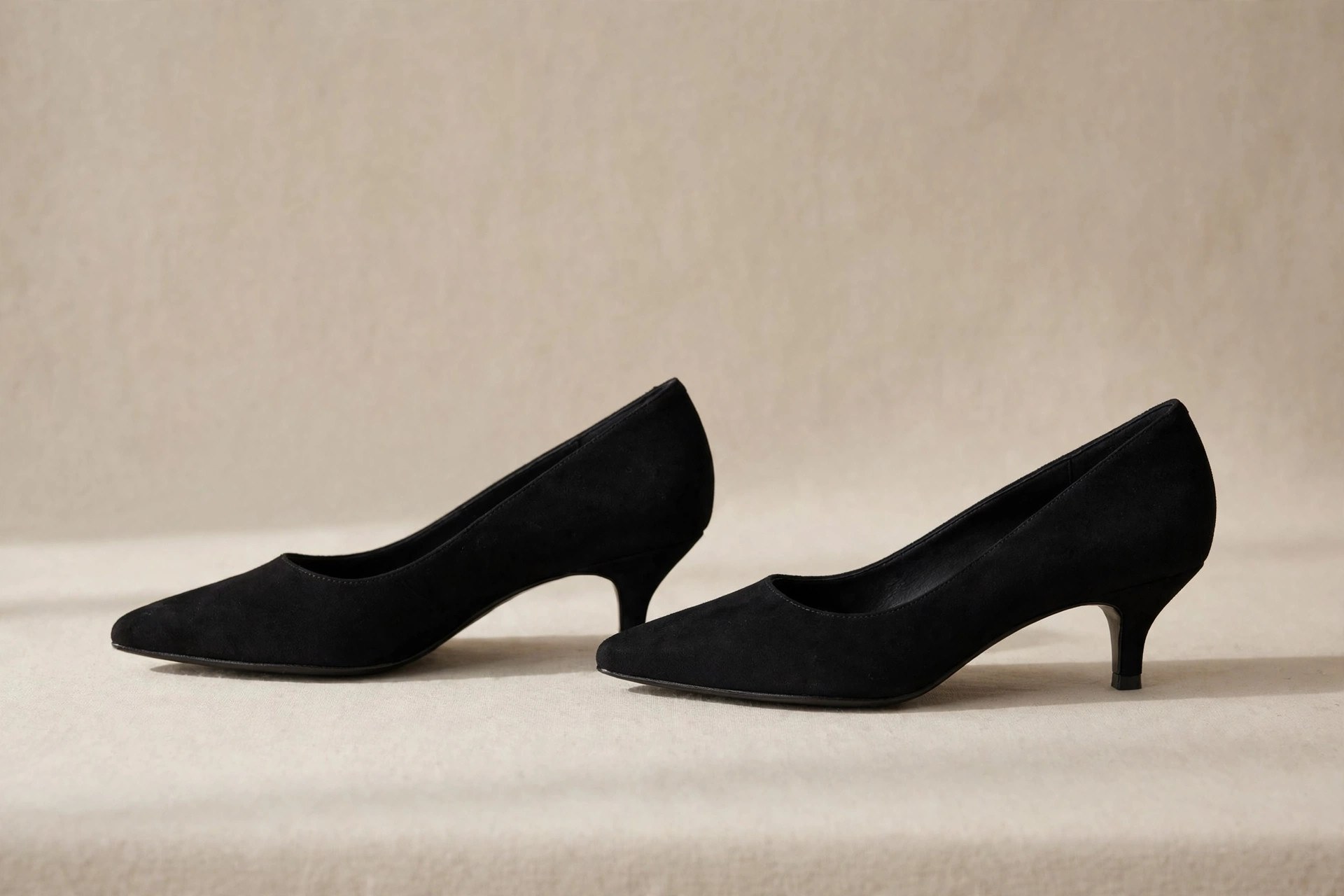Pair of black kitten heel pumps on a neutral studio background
