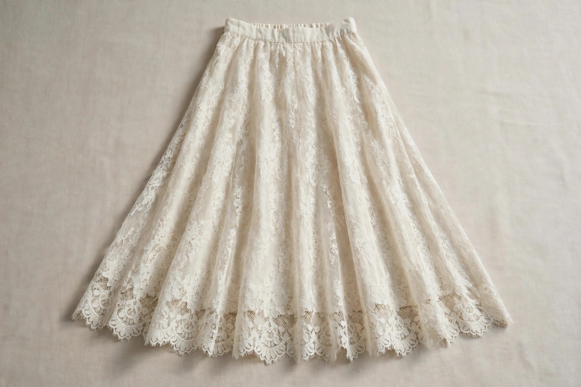 Ivory lace midi skirt laid flat, showing the floral openwork pattern and smooth lining beneath
