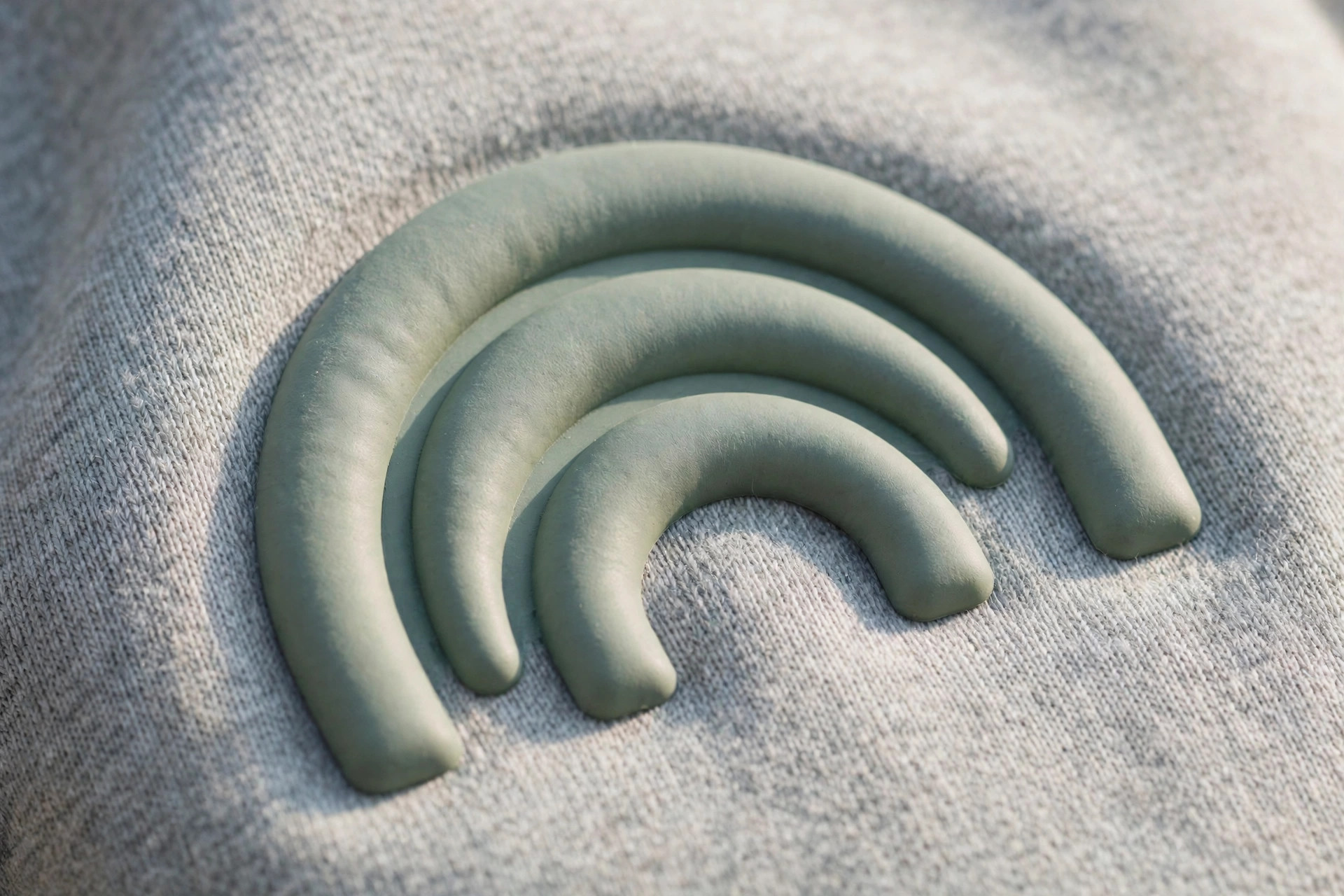 Close-up of a raised puff print logo on a sweatshirt showing the rounded three-dimensional effect