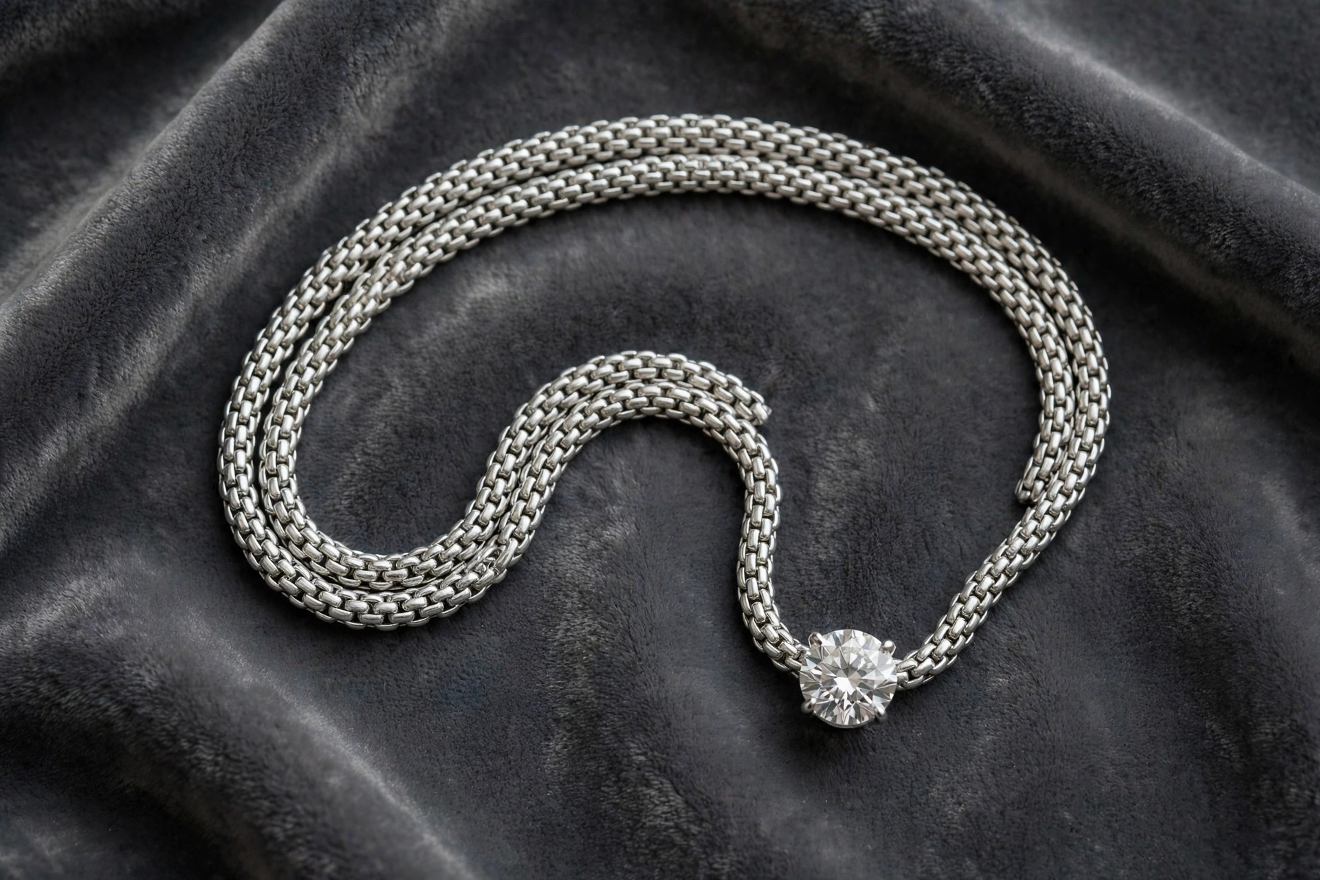 Platinum necklaces with a dense white platinum chain and diamond pendant on dark grey velvet