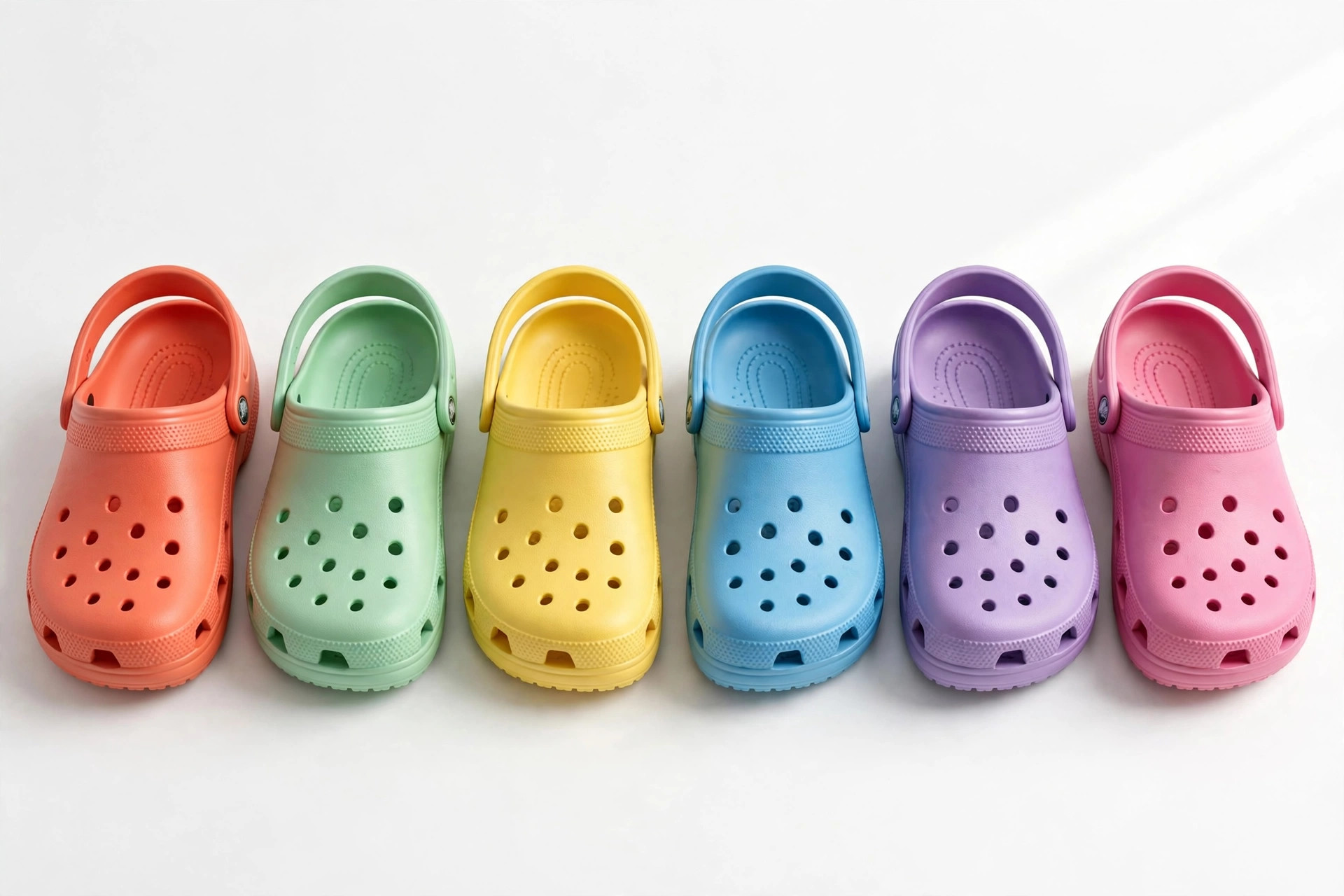 A row of colourful moulded clog shoes in several bright colours on a white studio background, product photography with no people