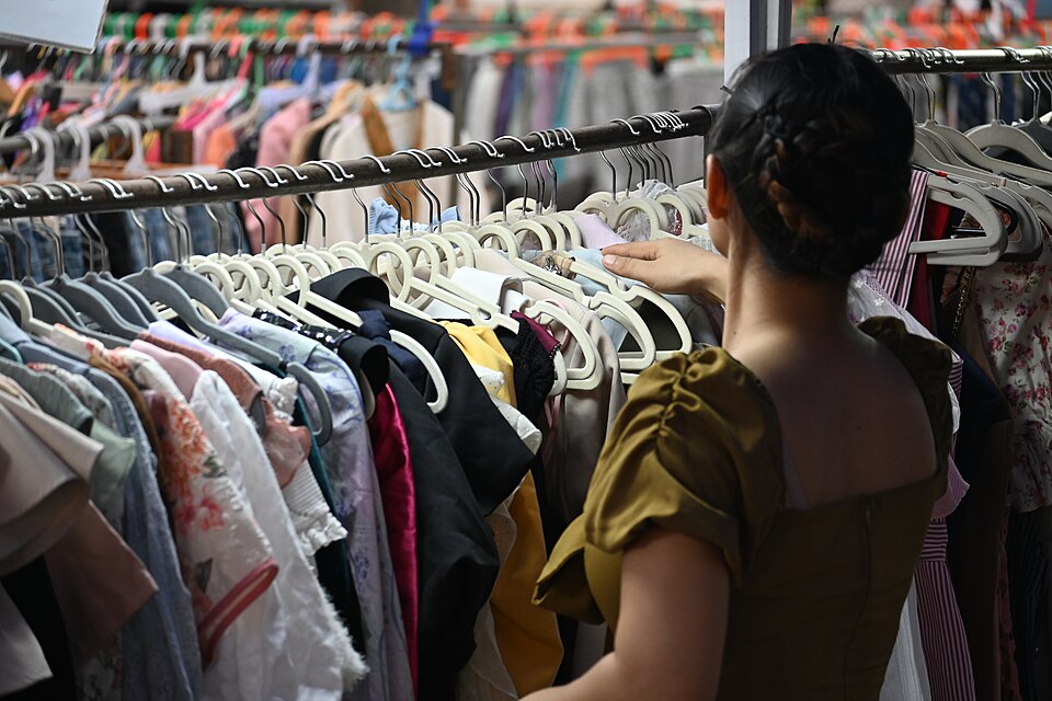 A shopper browsing a rack of colorful dresses
